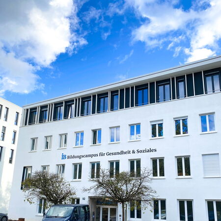 Ein modernes weißes Gebäude des Bildungscampus für Gesundheit und Soziales vor einem blauen Himmel mit Wolken.