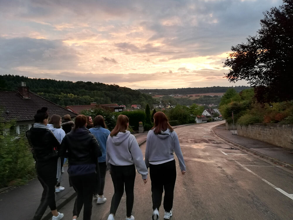 Eine Gruppe von Menschen spaziert bei Sonnenuntergang auf einer ruhigen Landstraße.