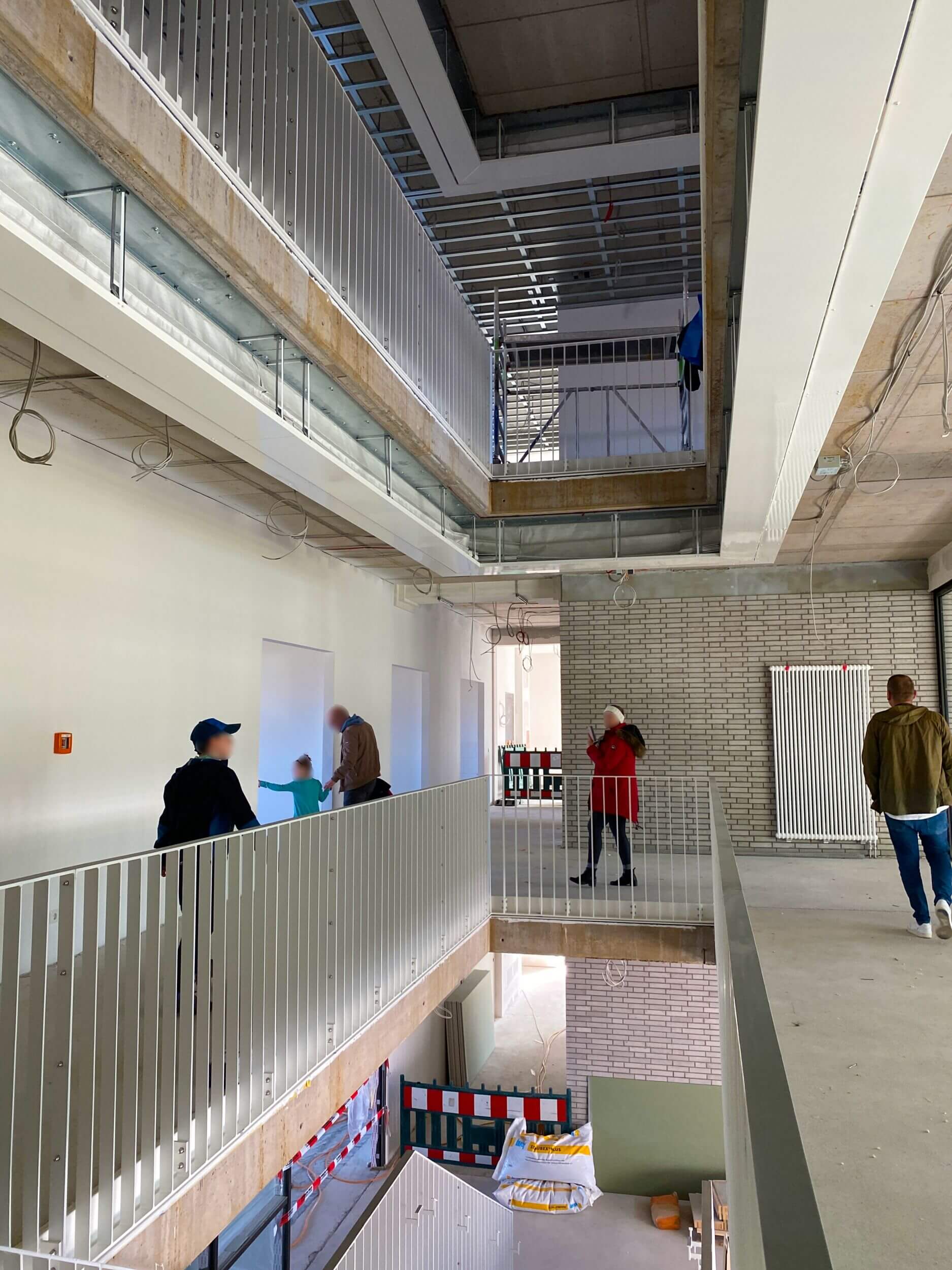 Im Treppenhaus der neuen Grundschule Flugfeld erkunden Menschen die Baustelle und begutachten den Fortschritt.