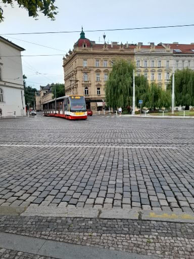 Eine Straßenbahn fährt über das Kopfsteinpflaster in einer ruhigen städtischen Umgebung mit historischen Gebäuden.