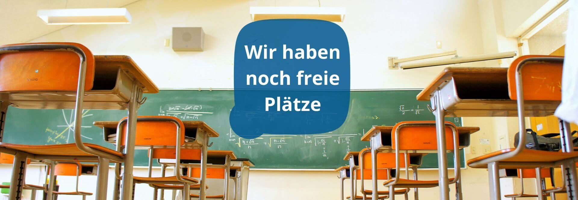 Ein leeres Klassenzimmer mit hochgestellten Stühlen zeigt eine Tafel mit der Aufschrift "Wir haben noch freie Plätze".