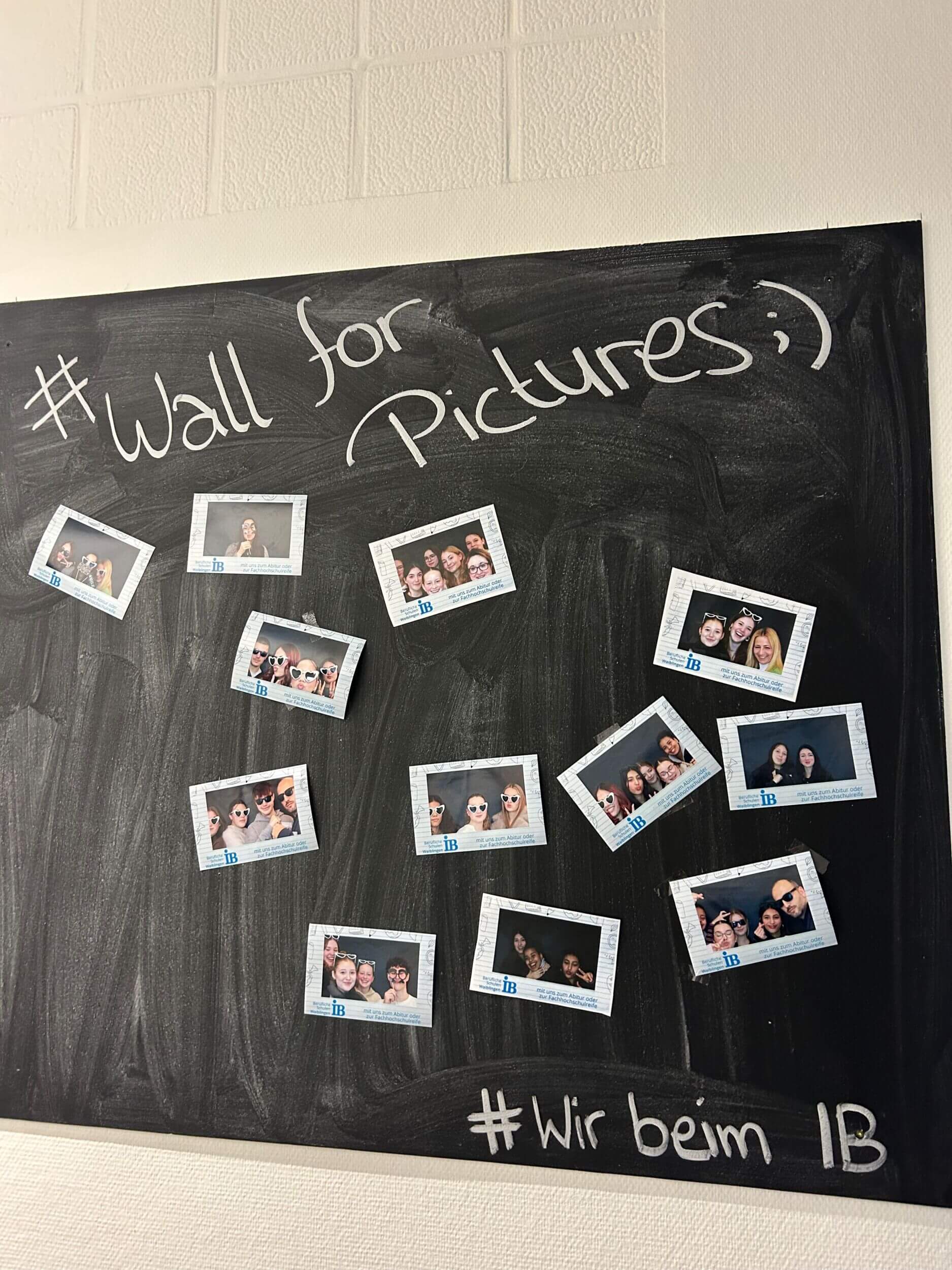 Mehrere Polaroid-Fotos von lachenden Menschen hängen an einer Tafel mit der Aufschrift „Wall for Pictures ;)“.